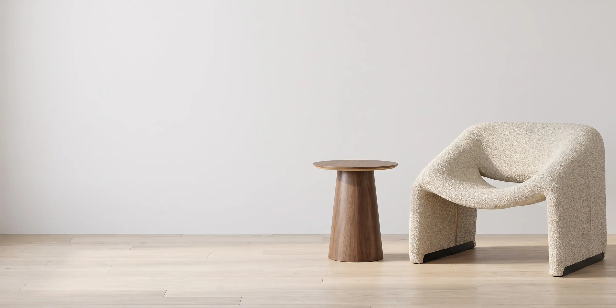 Sillón Bella greige de bouclé junto a la Mesa Lateral Padar de nogal en una sala blanca con piso de roble